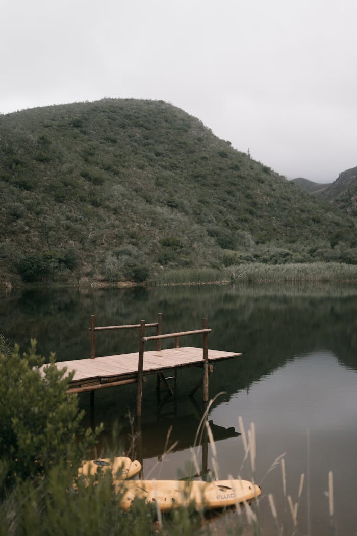 Home Peaceful lake scene featuring a wooden dock and lush mountains, perfect for tranquility seekers.